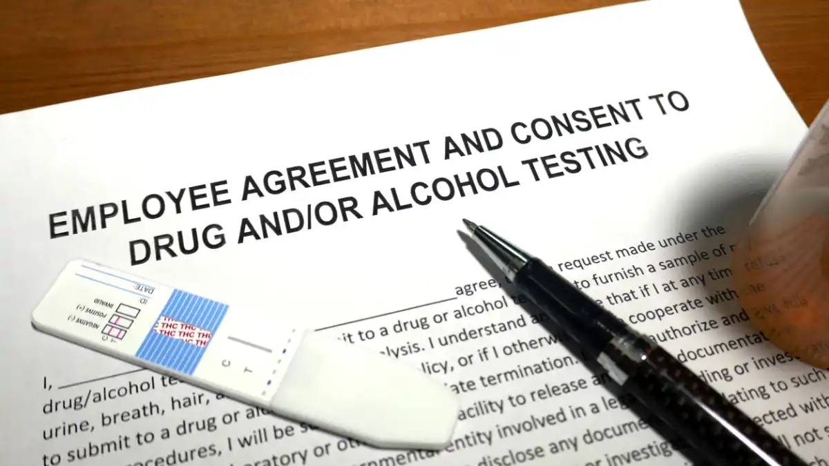 An "Employee Agreement and Consent to Drug and/or Alcohol Testing" form is presented with a drug test kit and a pen on top.