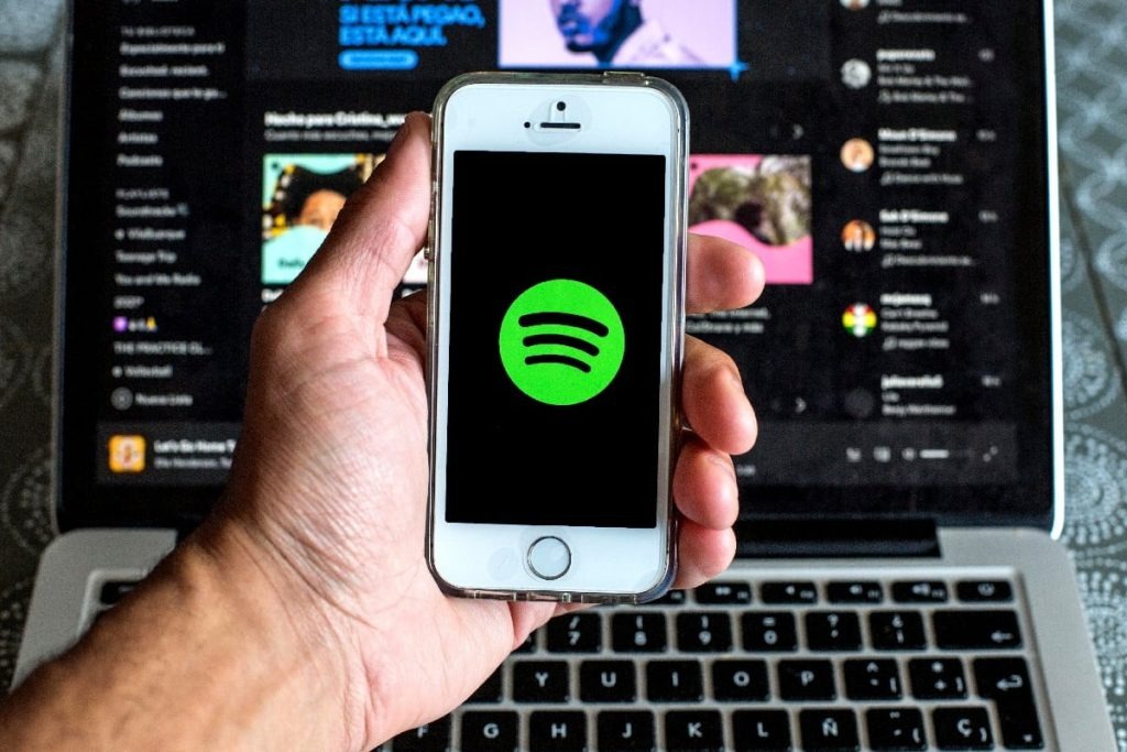 A person holding a mobile with Spotify logo