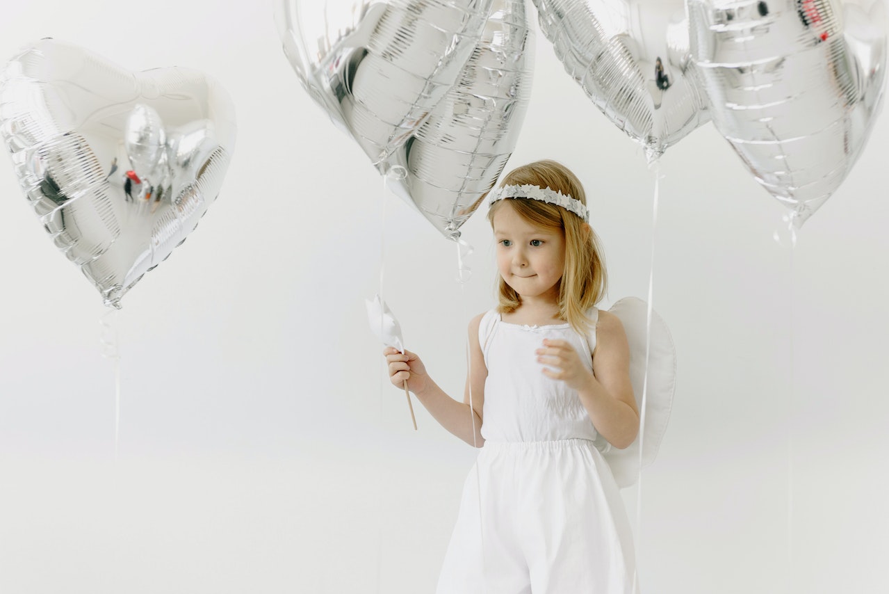 A Girl in a White Dress with Heart Shaped Balloons
