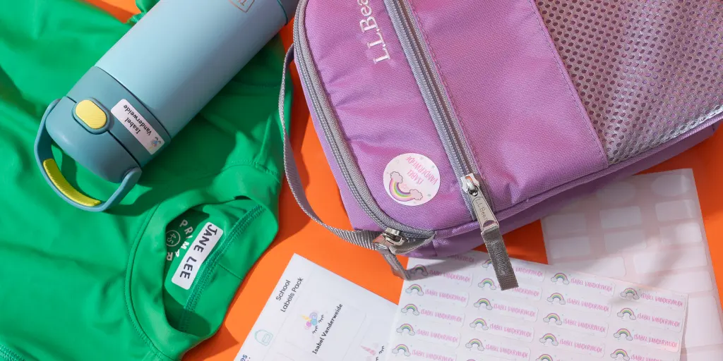 Colorful school or travel essentials, including a water bottle, a pink mesh bag, a green shirt, and various labels on a vibrant orange background.