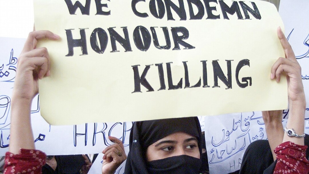 A woman holding a sign about honor killing