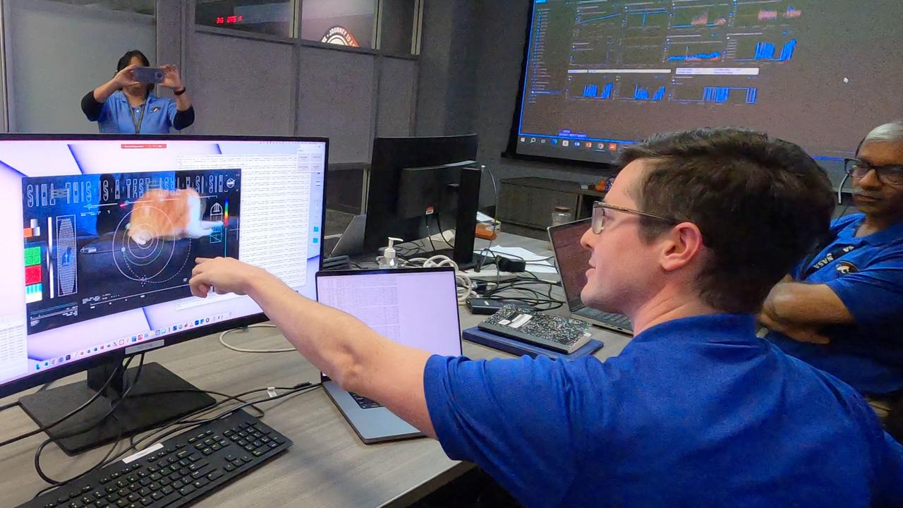 A man pointing at the monitor with a video of a cat sent to NASA