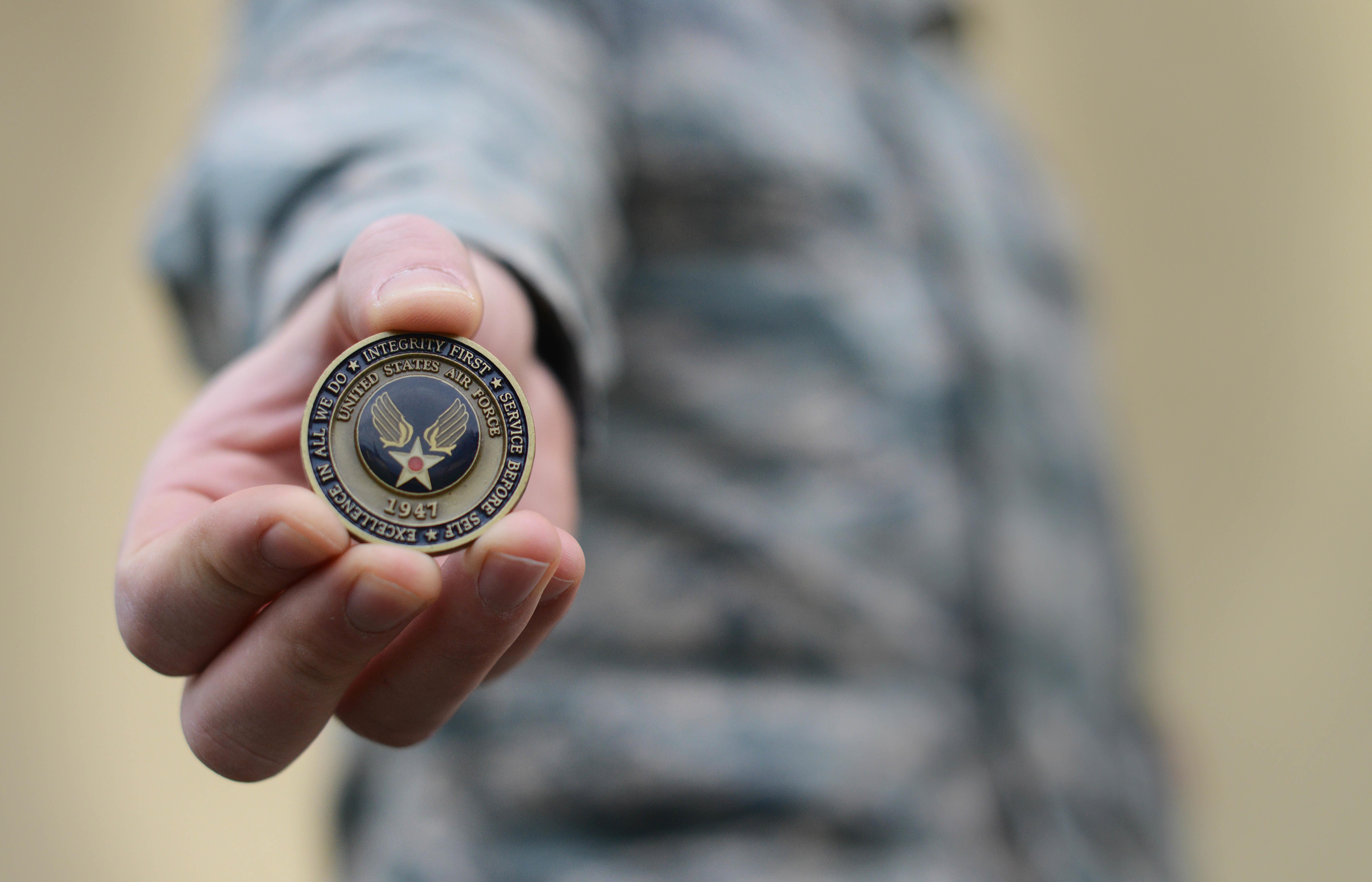 A hand holding a challenge coin