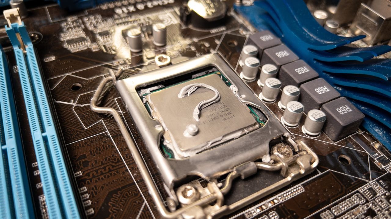 Central processing unit (CPU) with a question mark-shaped application of thermal paste, highlighting a unique method of preparing for heat sink attachment.