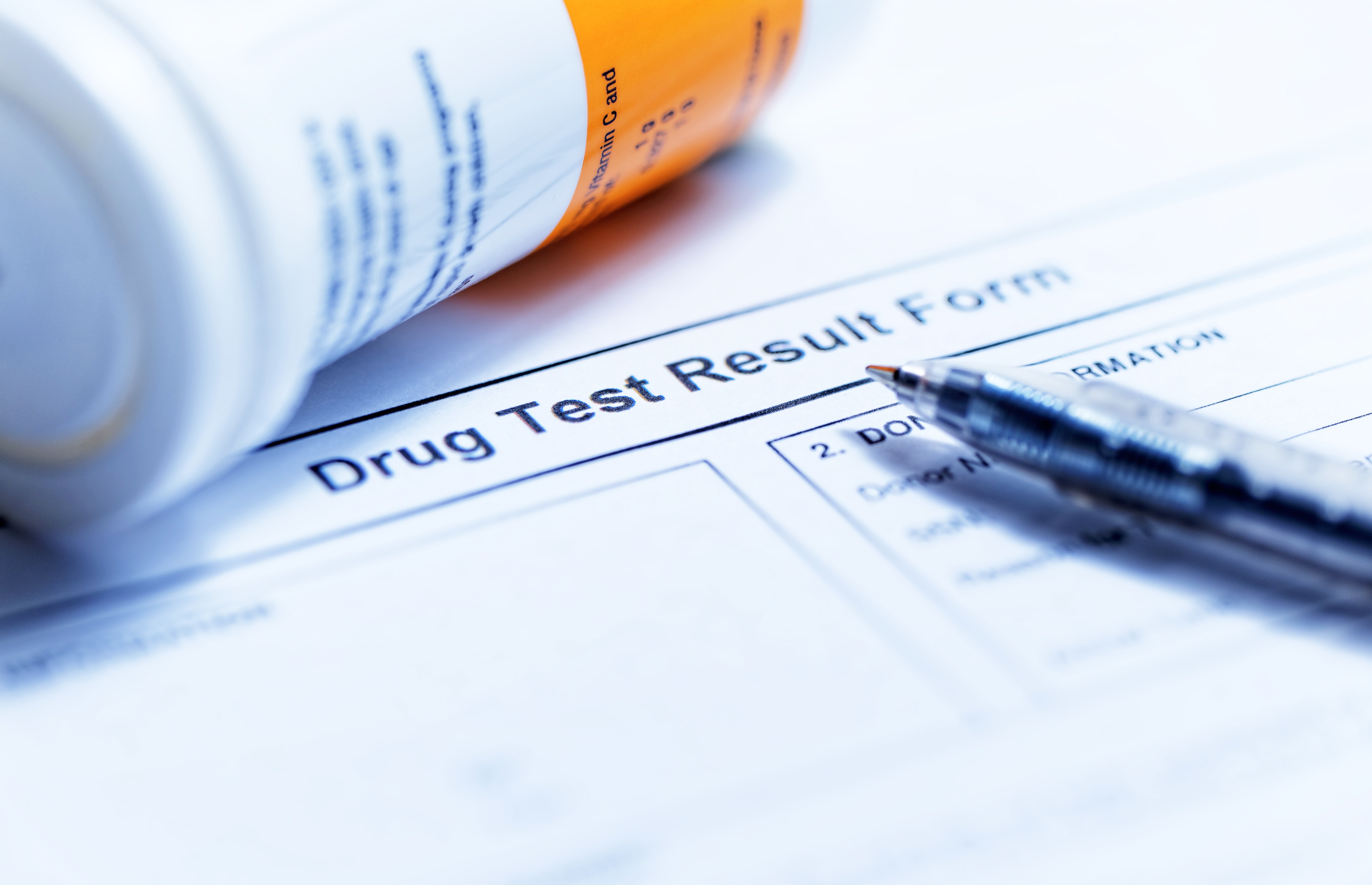 A "Drug Test Result Form" is laid out with a pen on top, adjacent to a prescription bottle.