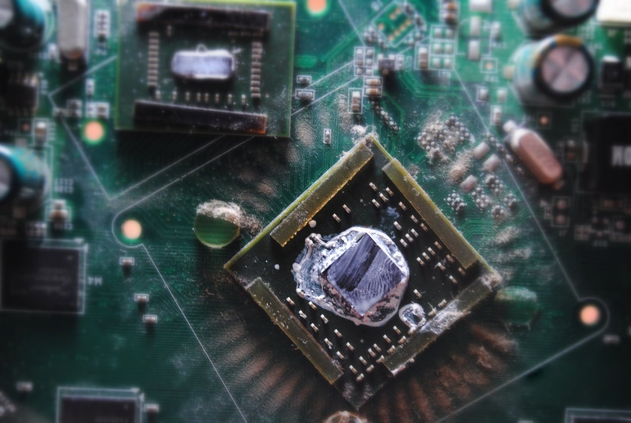 Circuit board with a central chip covered in dried and possibly cracked thermal paste, indicating a need for maintenance or repair.