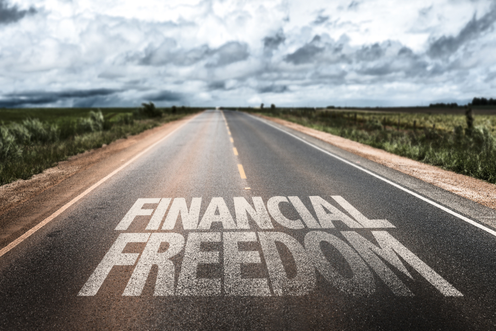 A road with the words "FINANCIAL FREEDOM" written on it, symbolizing the journey towards financial independence.