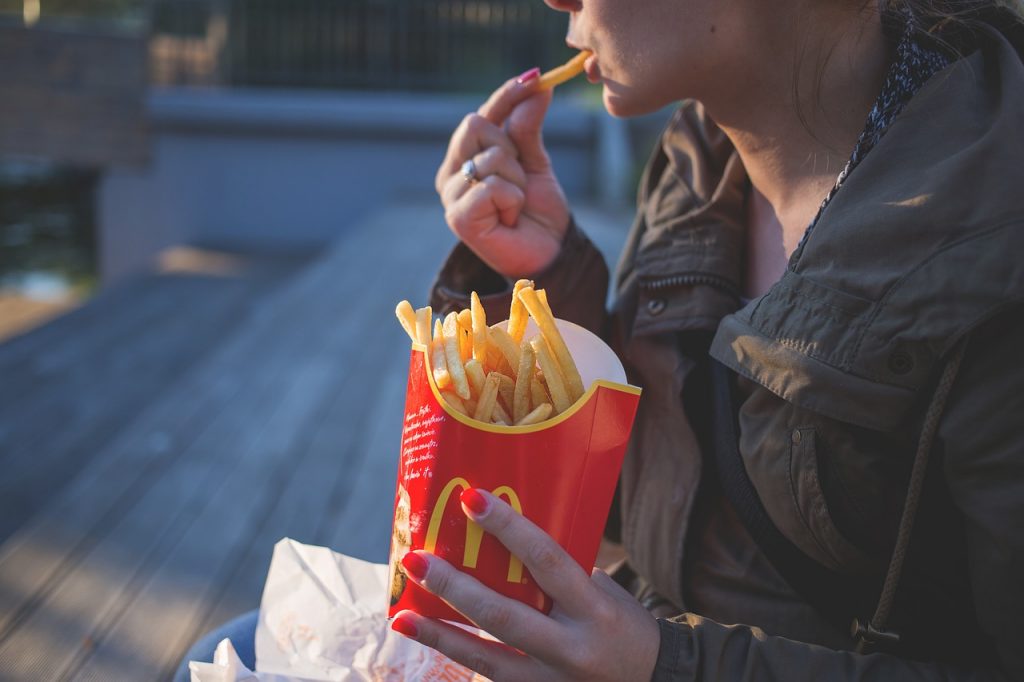 A girl eating MacDonald's fries.