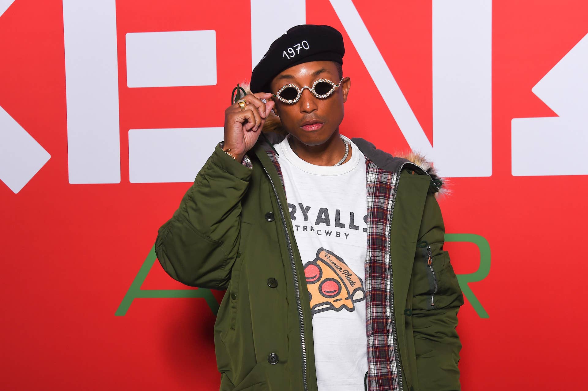 Pharrell Williams wearing a green jacket and sunglasses