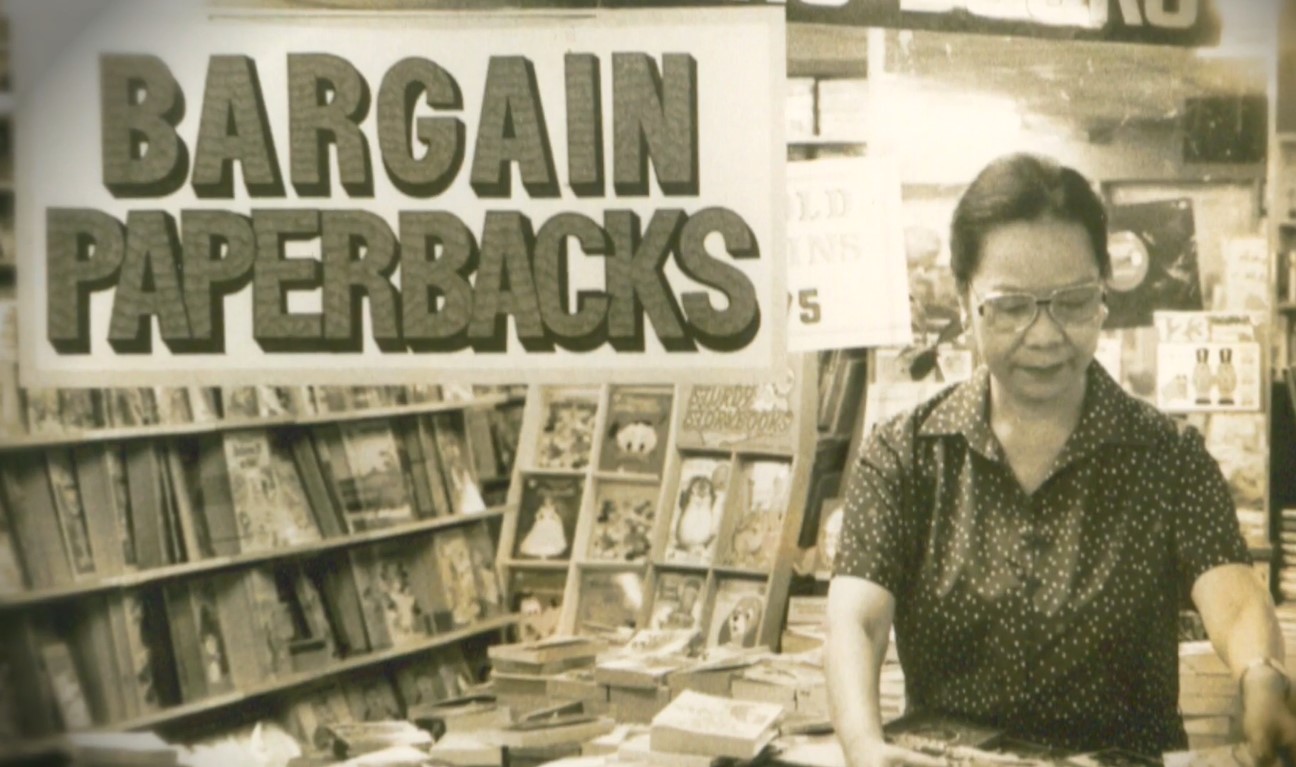 Socorro Ramos standing near the sign ‘Bargain Paperbacks’ while arranging books at National Book Store