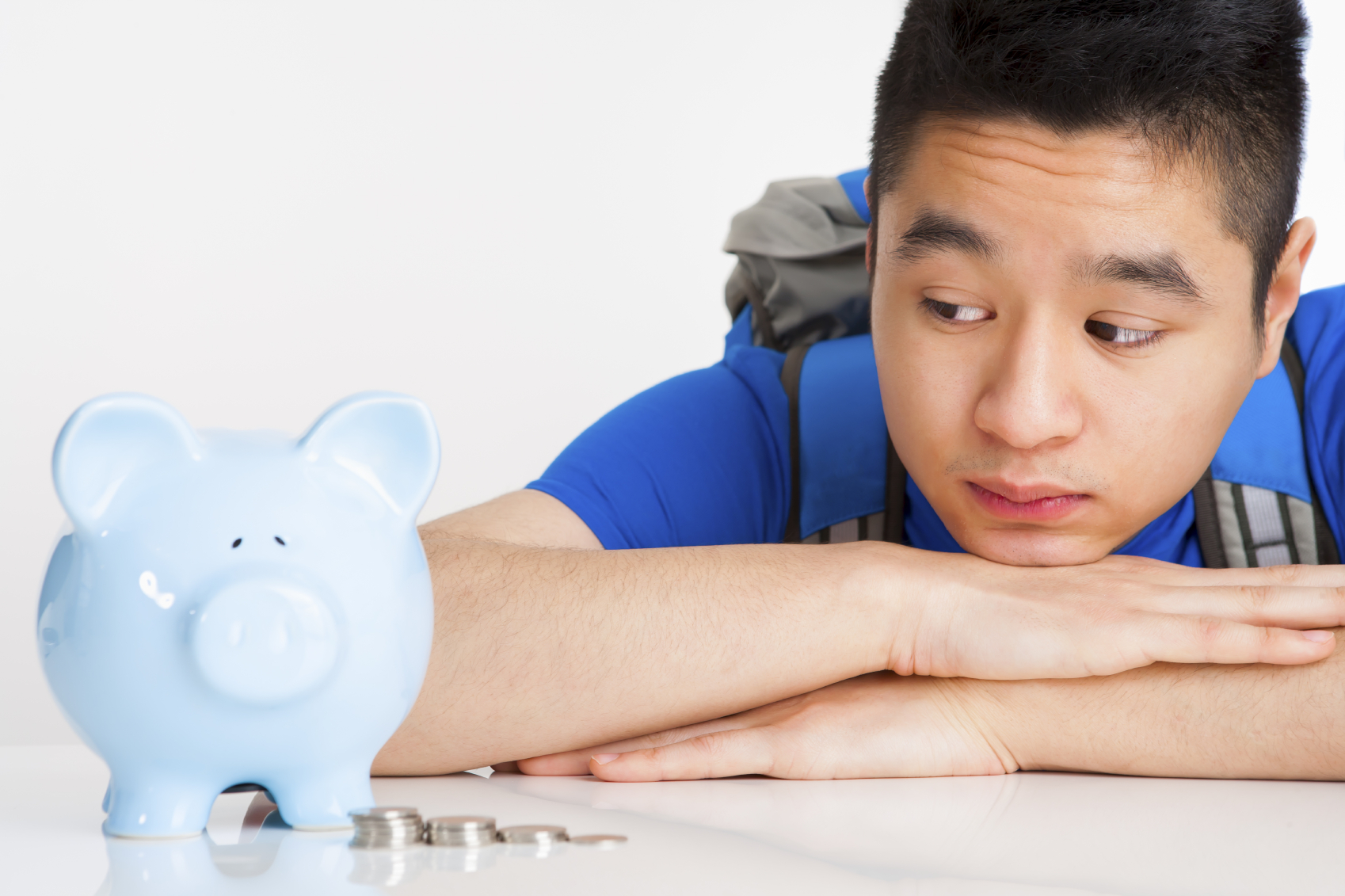 A teenage boy looking at a blue piggy bank