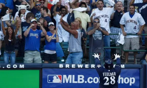 Milwaukee Brewers player named Fielder celebrating with raised arms in front of an exuberant crowd, capturing a moment of excitement at a baseball game.