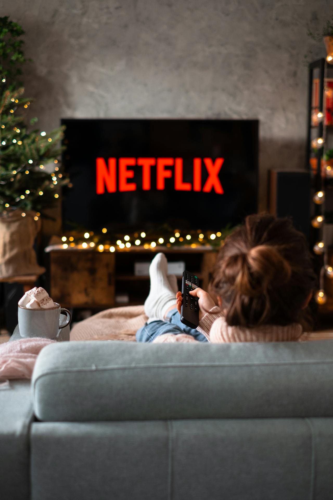 A woman is watching Netflix on TV while sitting in couch.