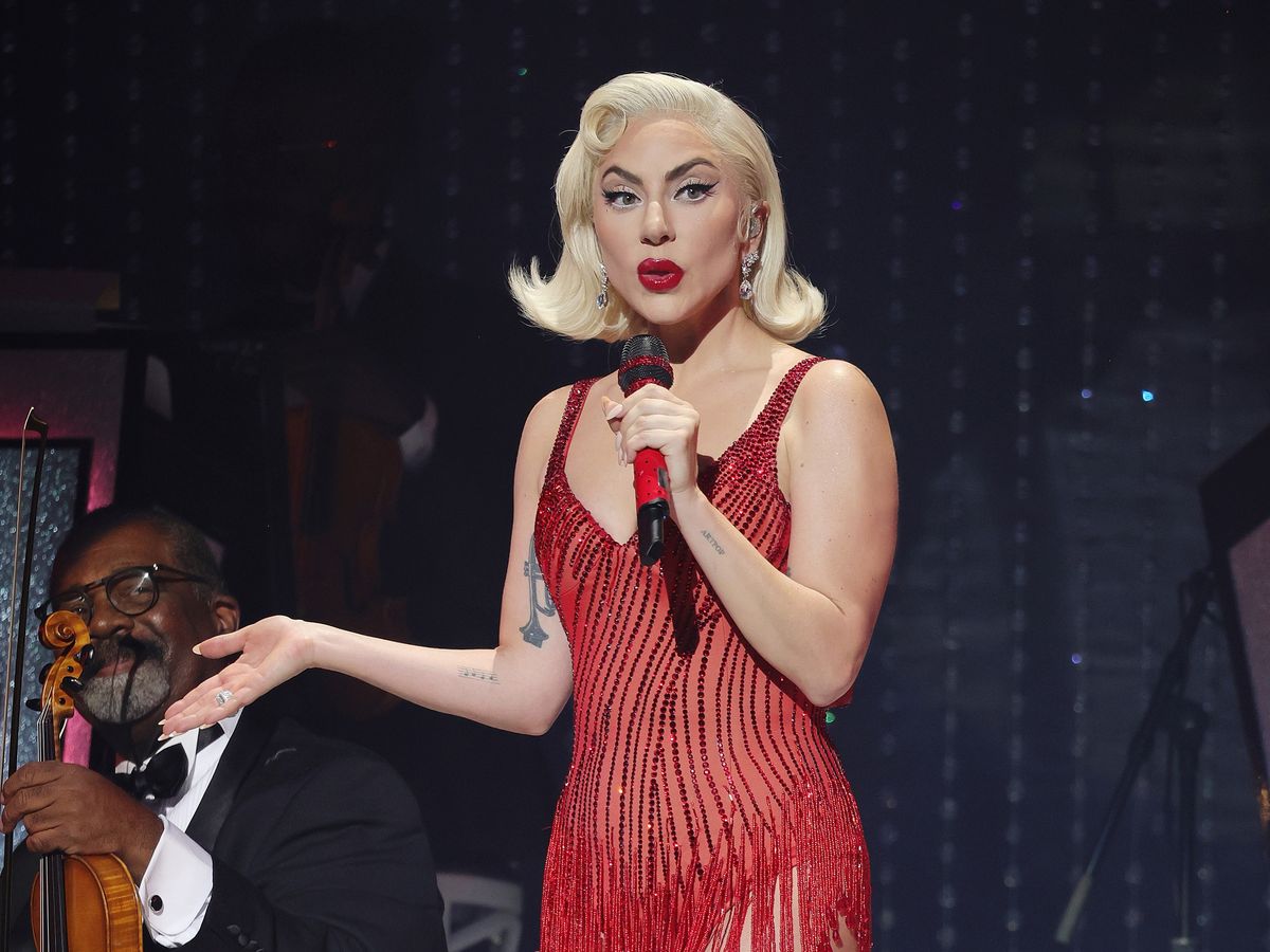 Lady gaga wearing a red dress while holding a mic