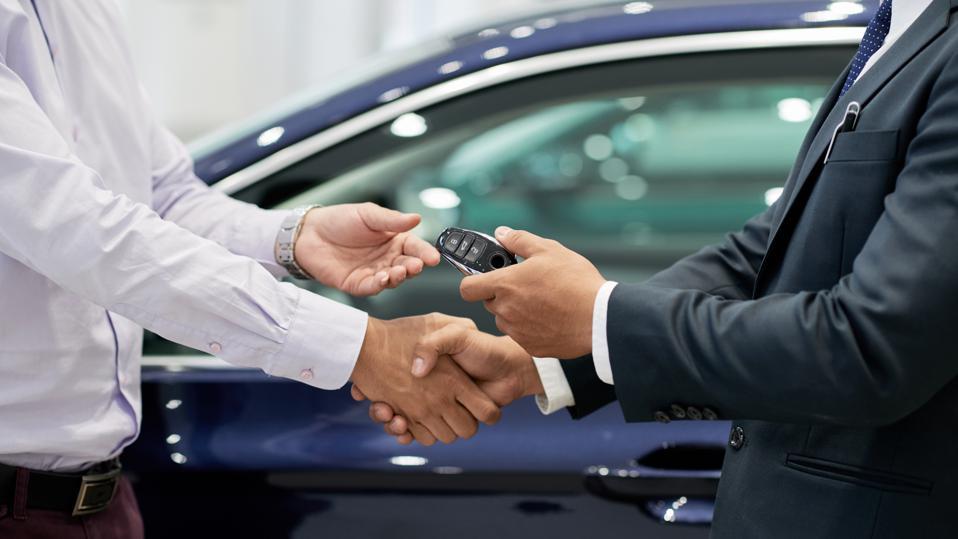 Car dealer handling car keys to customer