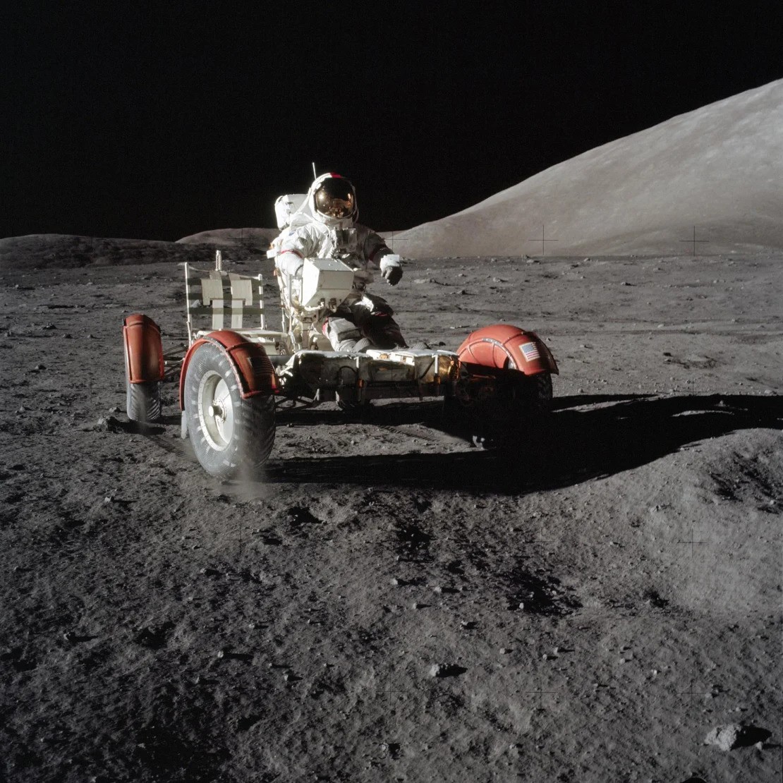 An astronaut driving a lunar roving vehicle on the moon's surface