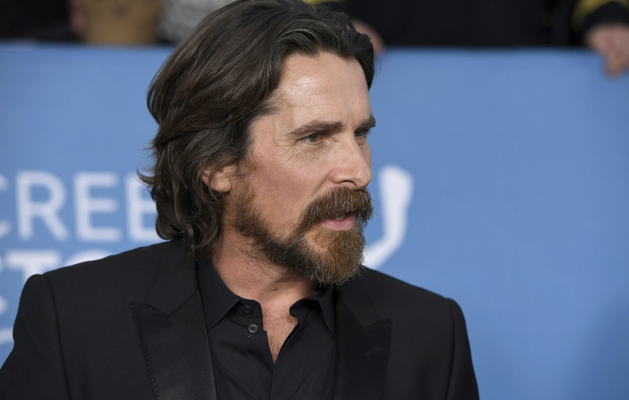 Christian Bale wearing a black coat