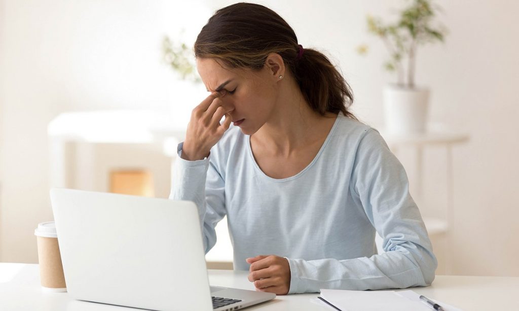A woman sitting in front of her laptop looking tired