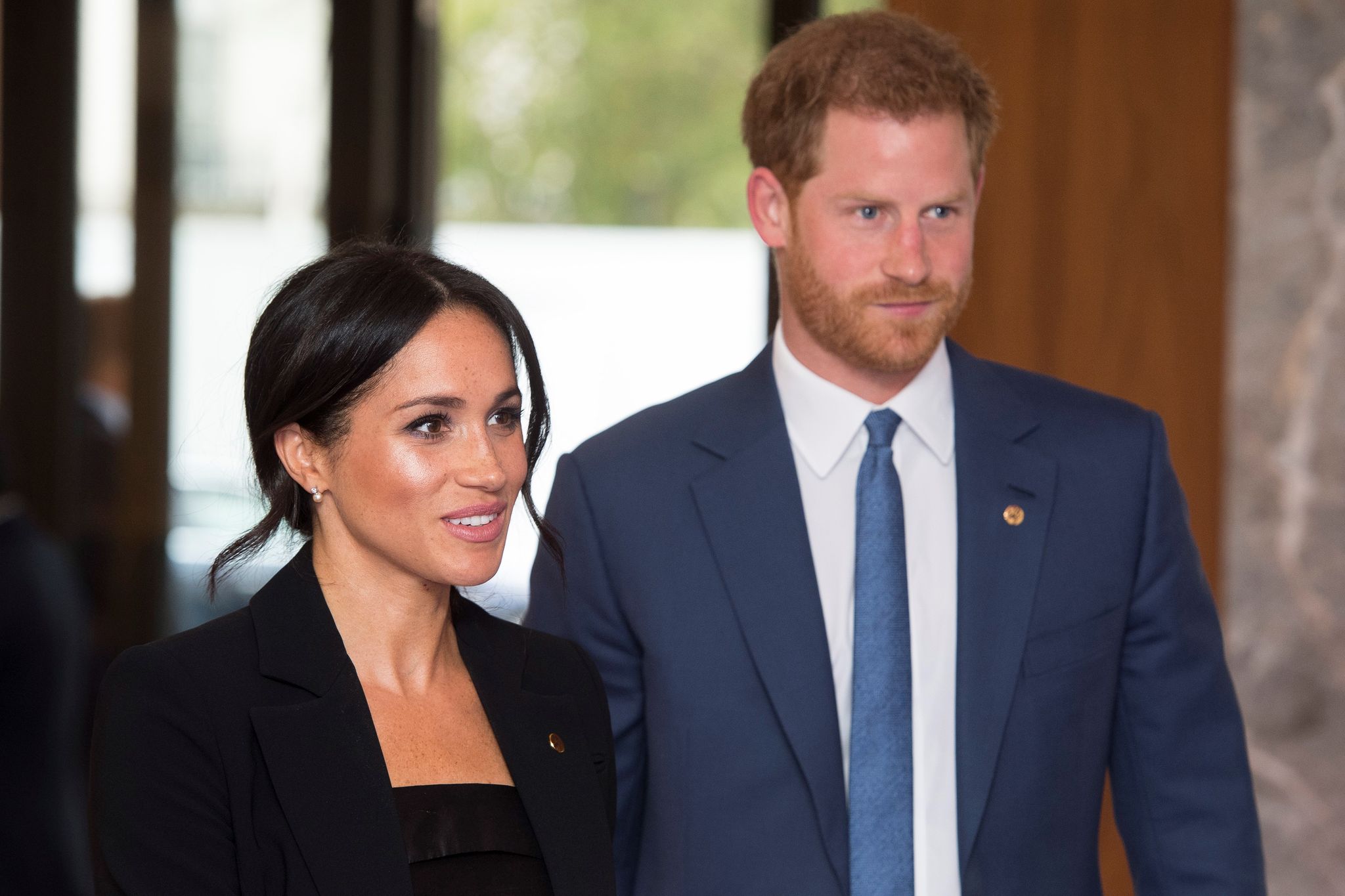 Meghan Markle wearing a black coat and Prince Harry wearing a blue coat