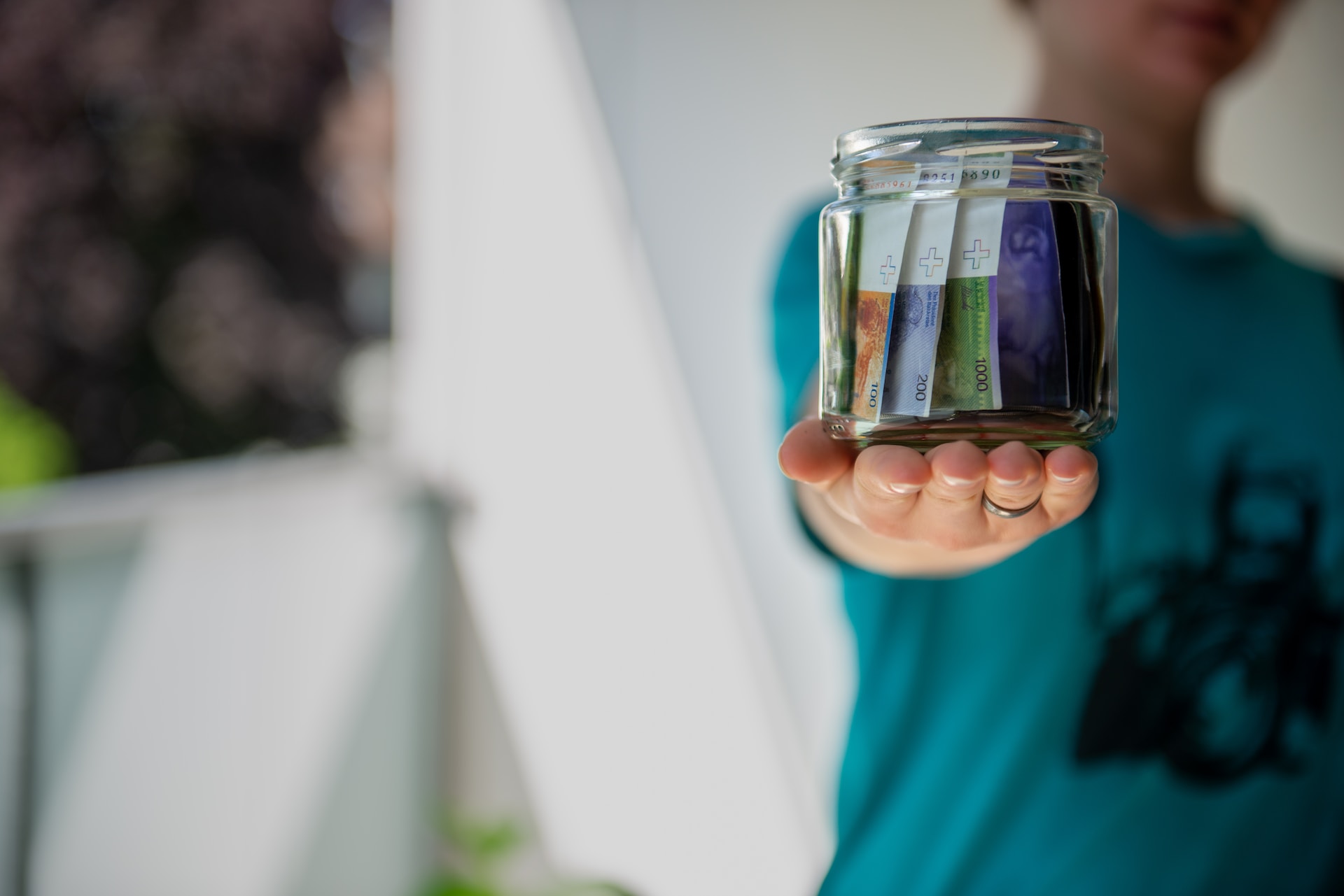 A person holding a glass jar filled with money