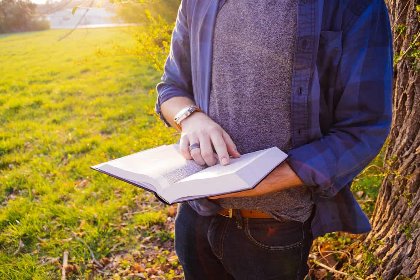A man is reading a book in a garden