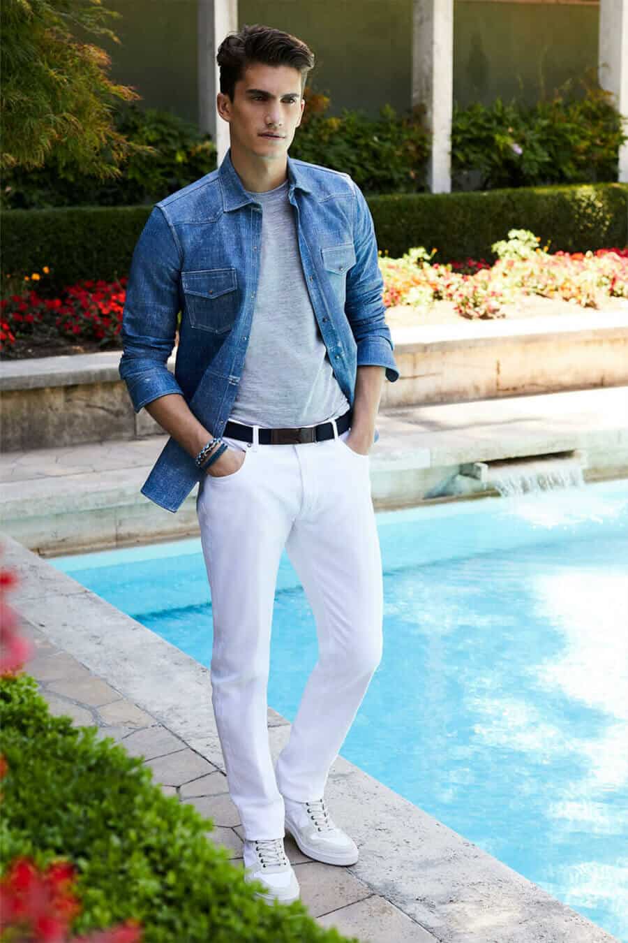 A man standing wearing white jeans.