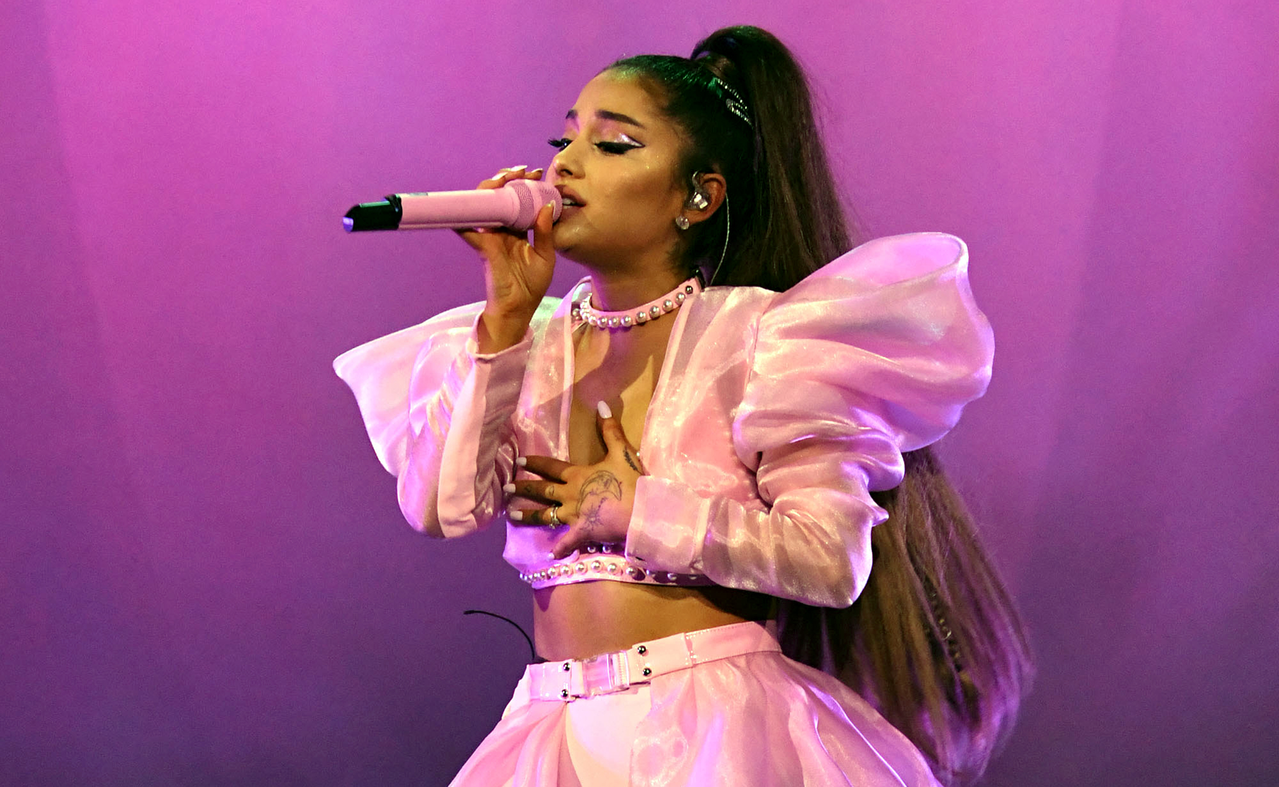 Ariana Grande wearing a pink outfit while holding a pink mic