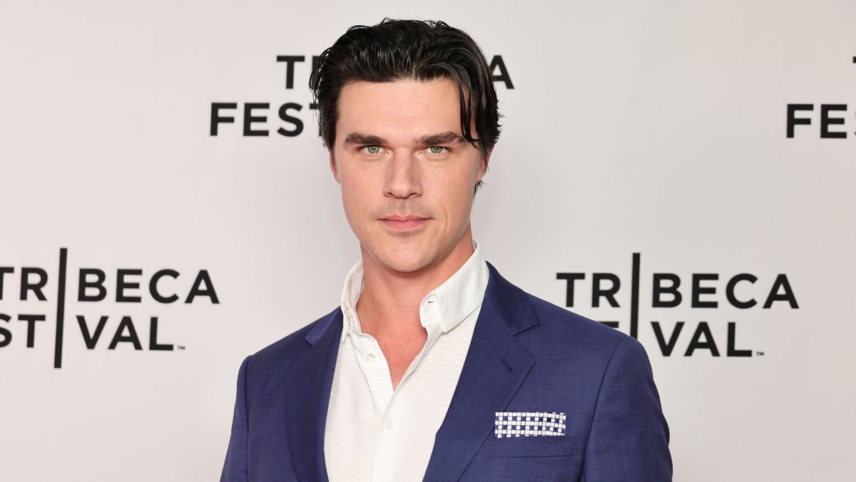 Finn Wittrock wearing a blue suit on a white shirt at an event