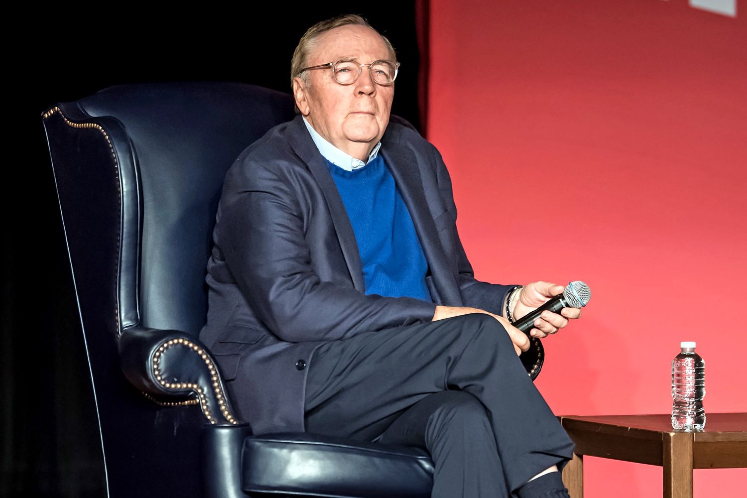 James Patterson wearing a black coat while holding a mic