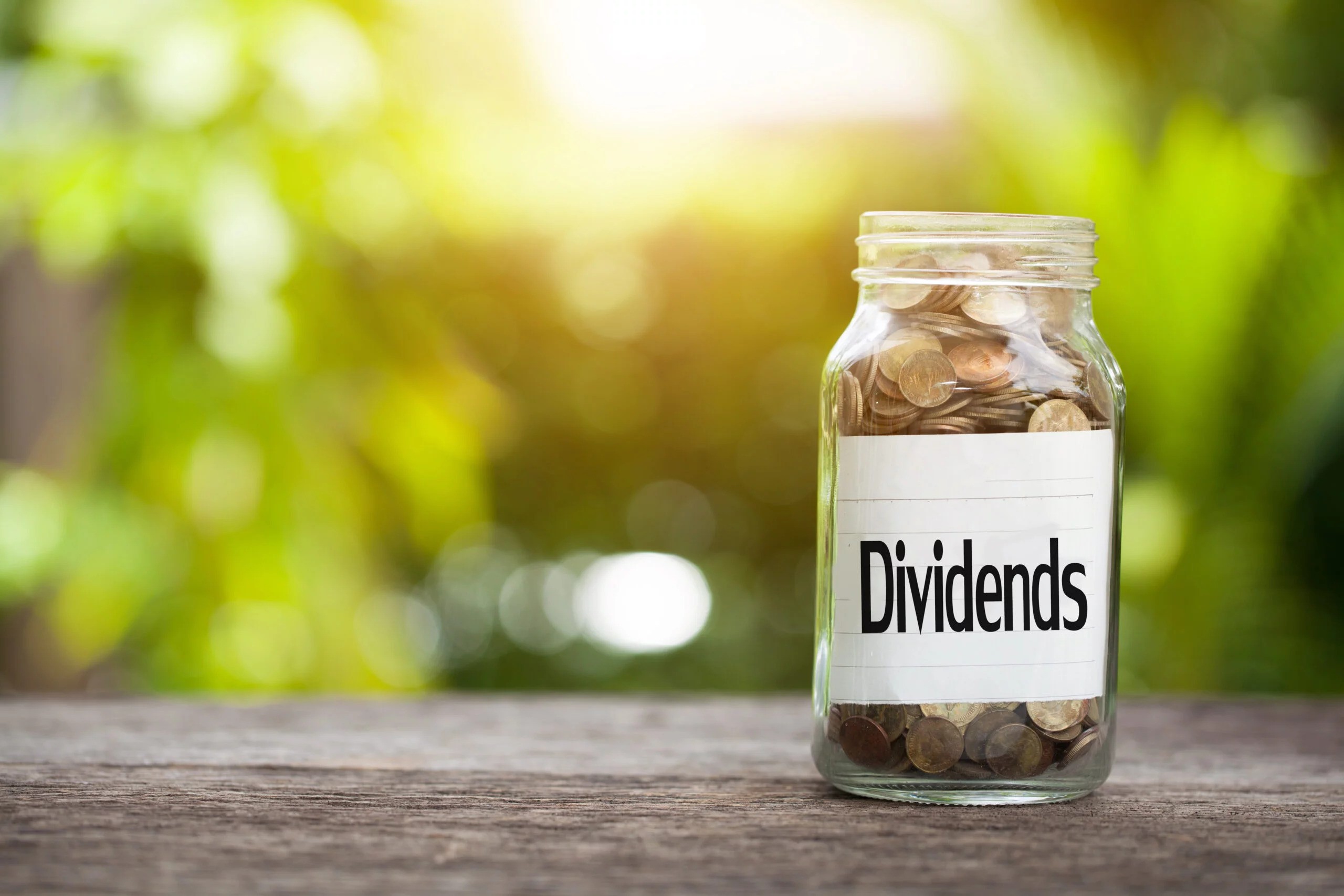A glass jar filled with coins with the word Dividend on it