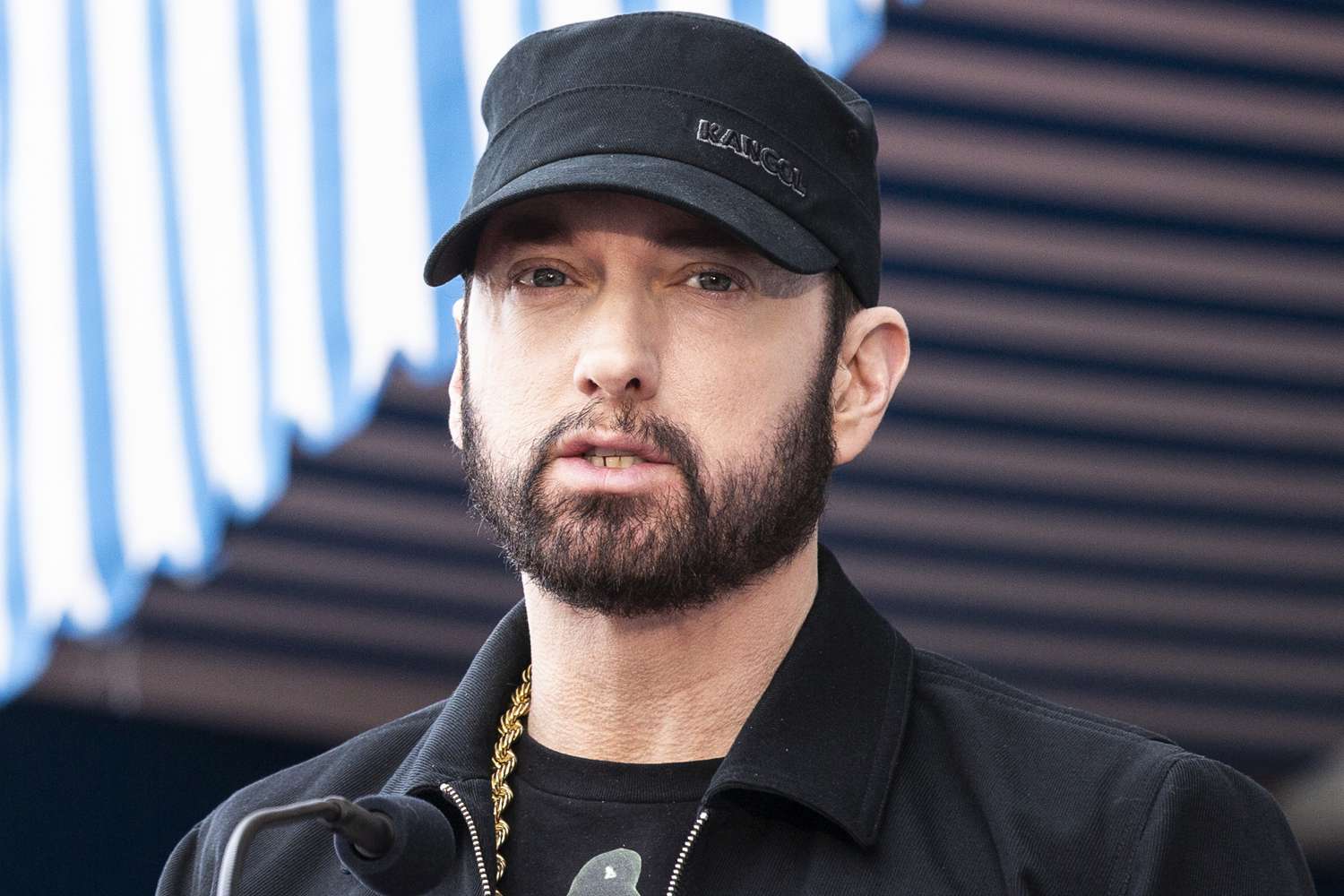 Eminem wearing a black jacket and cap
