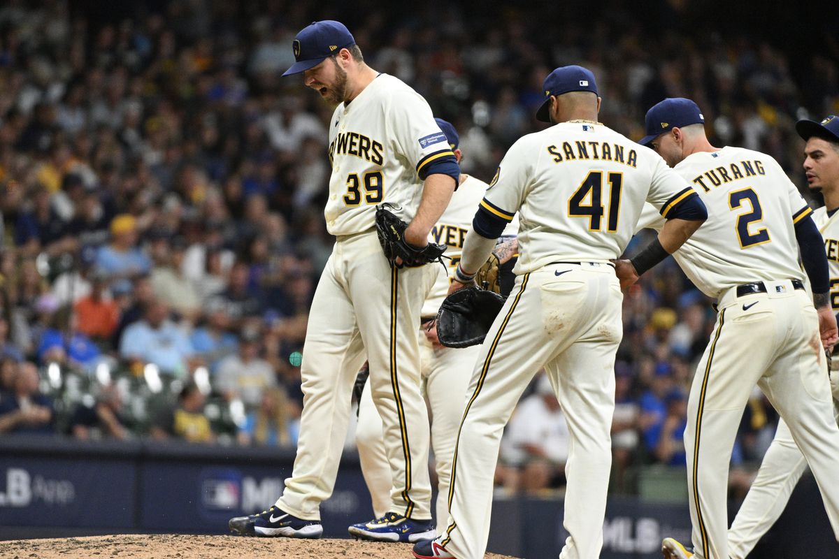 Milwaukee Brewers players on the field, with their names and jersey numbers visible, as they seem to be involved in a mid-game discussion or transition.
