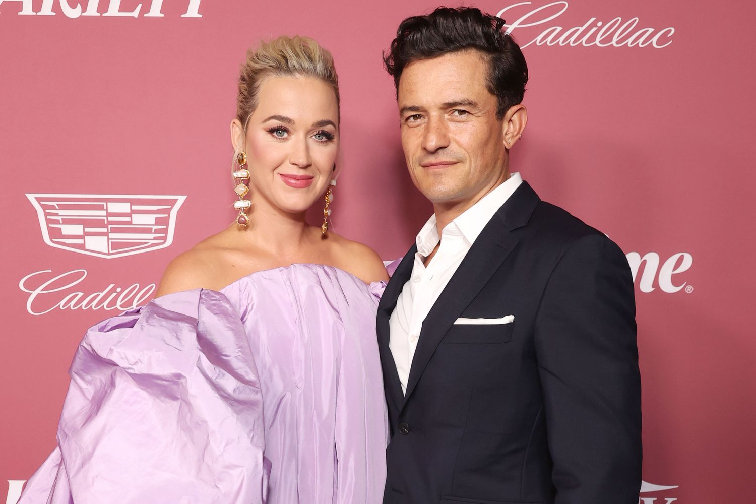 Katy Perry wearing a purple dress and orlando Bloom wearing a black suit