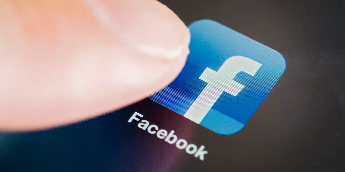 A finger clicking on Facebook icon