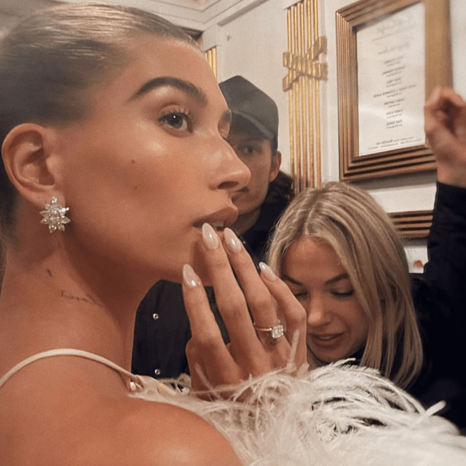 Hailey Bieber's finger close to her mouth as she attends an event