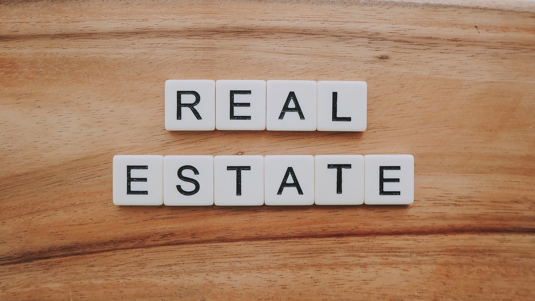  the words "REAL ESTATE" spelled out in Scrabble tiles on a wooden table.