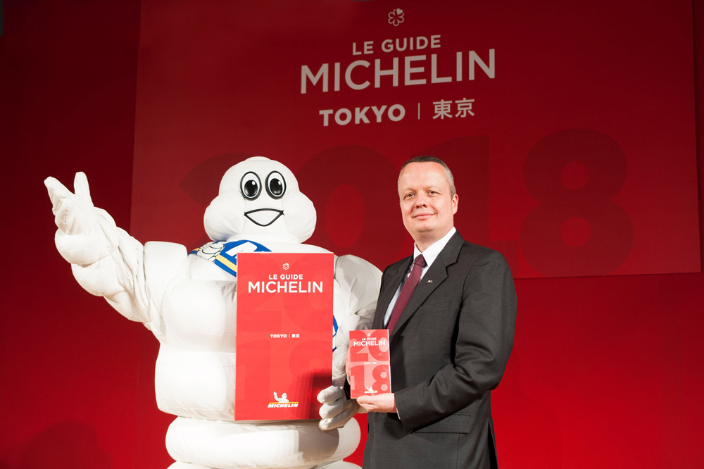A Michelin star guide held by a presenter and Michelin mascot during Michelin event 2018 in Tokyo