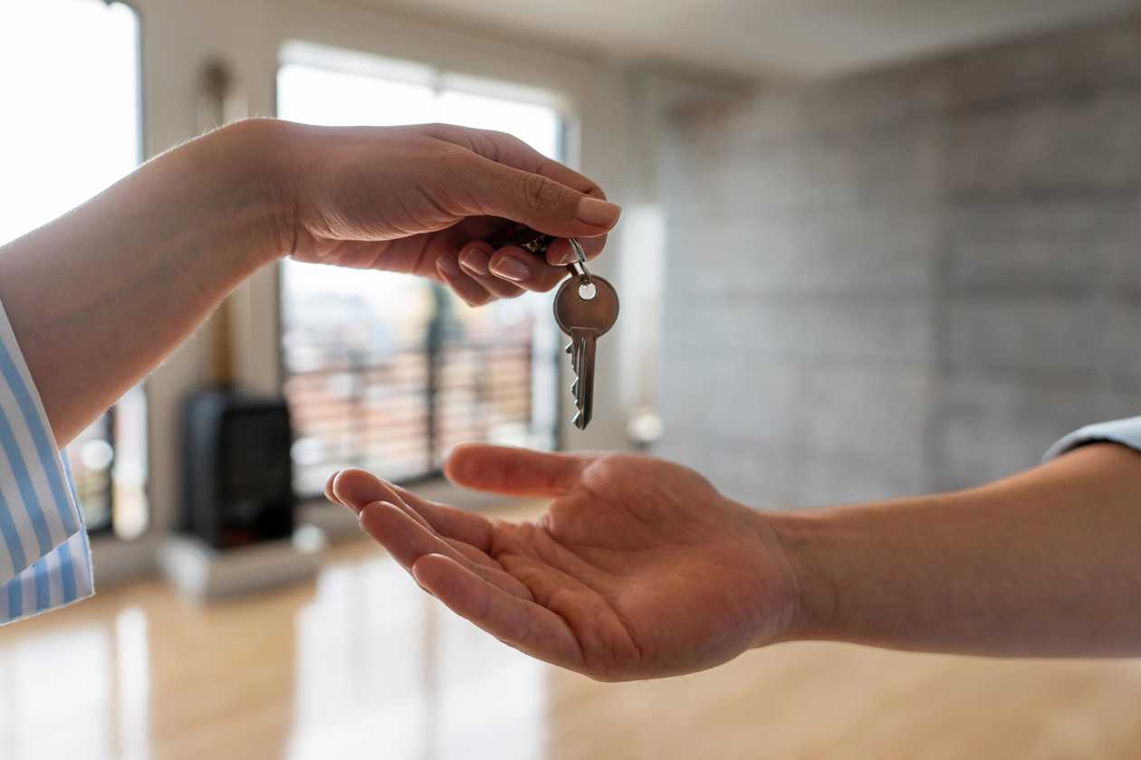 A hand receiving a house key from another hand