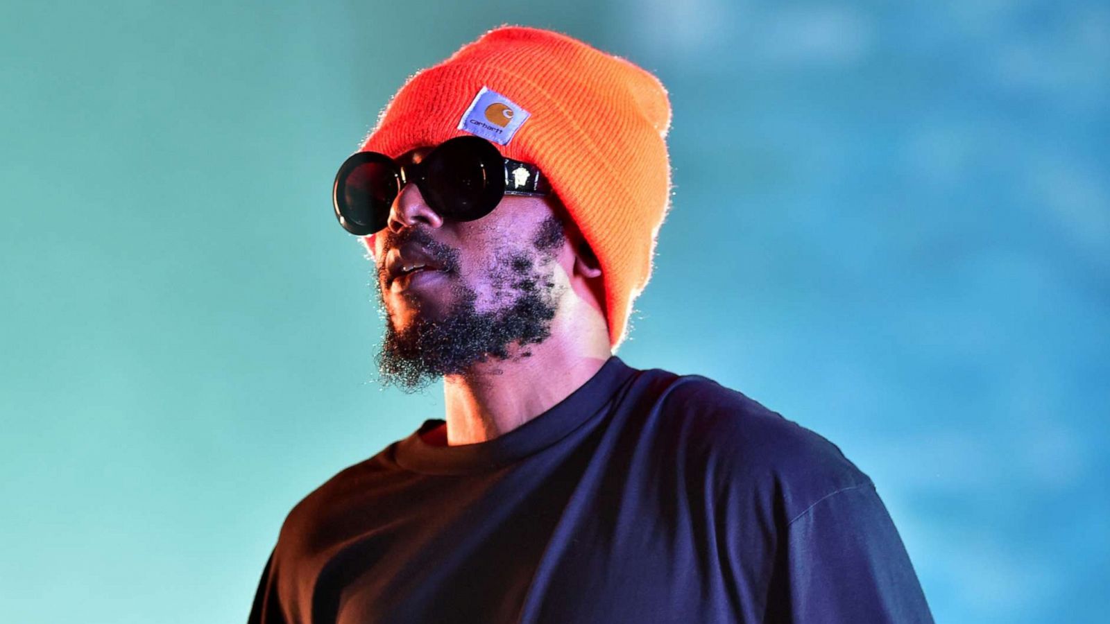 Kendrick Lamar wearing a black sweater and orange beanie