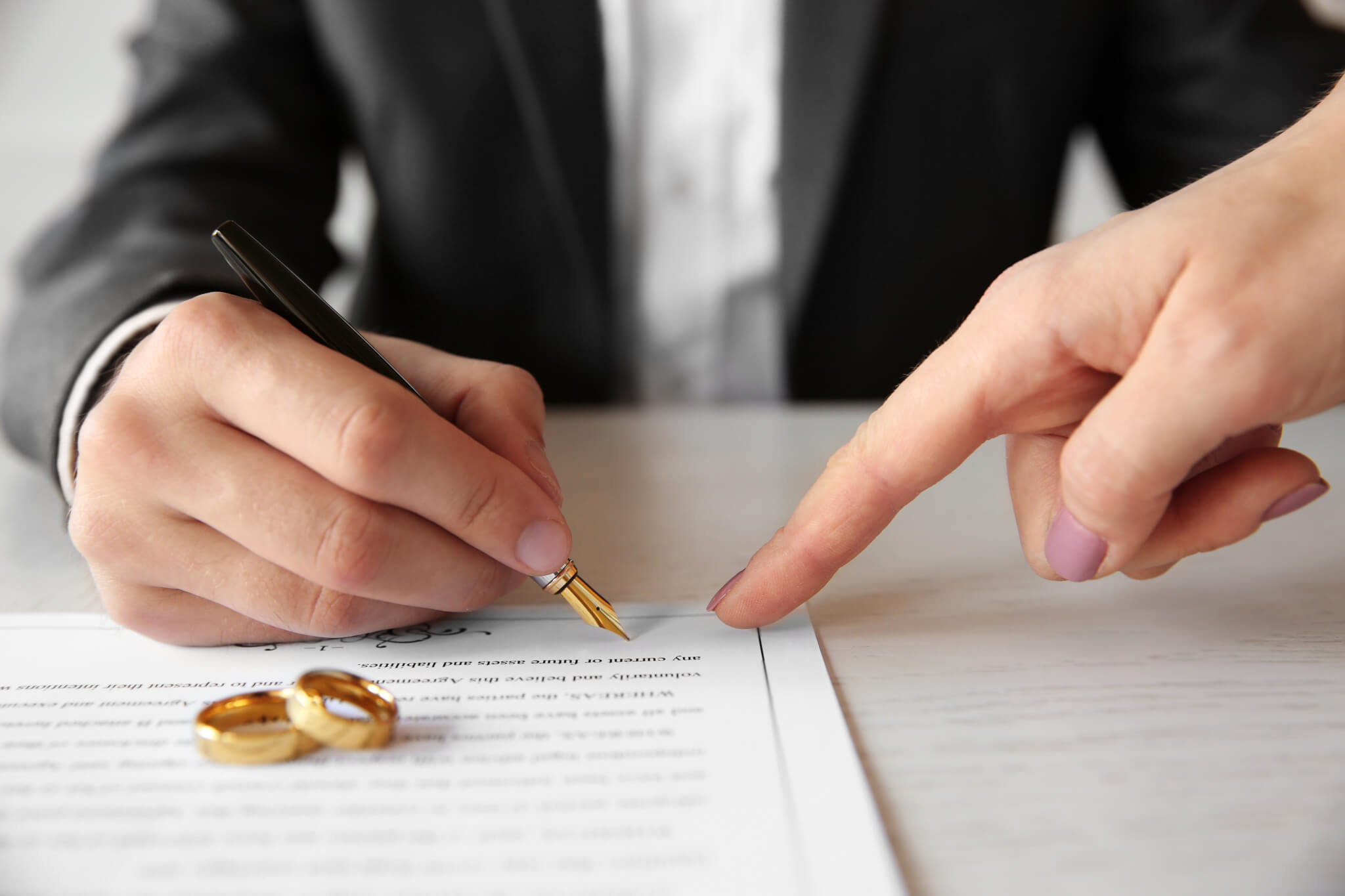 A person writing on a paper with gold rings on top of it