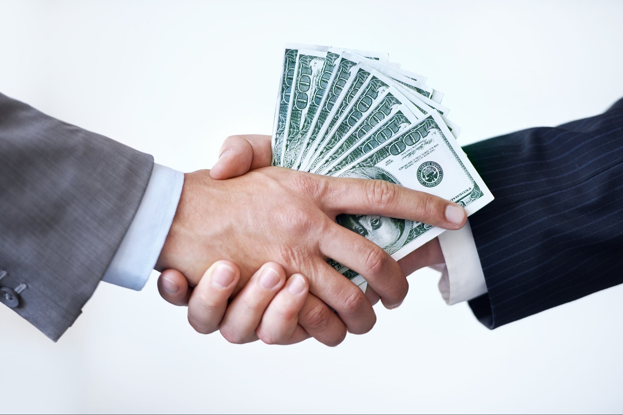Two people shaking hands with money