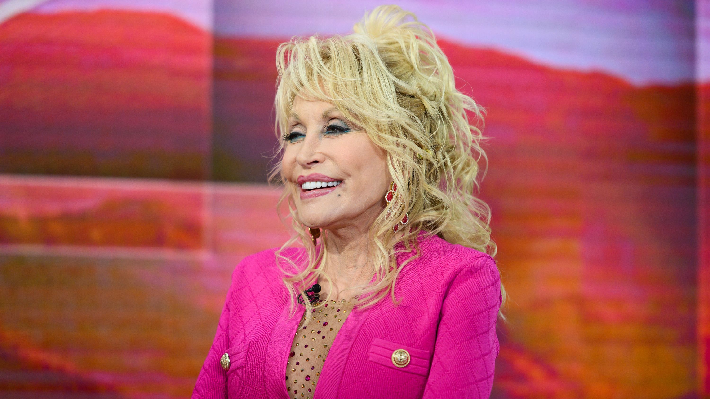 Dolly Parton wearing a pink coat
