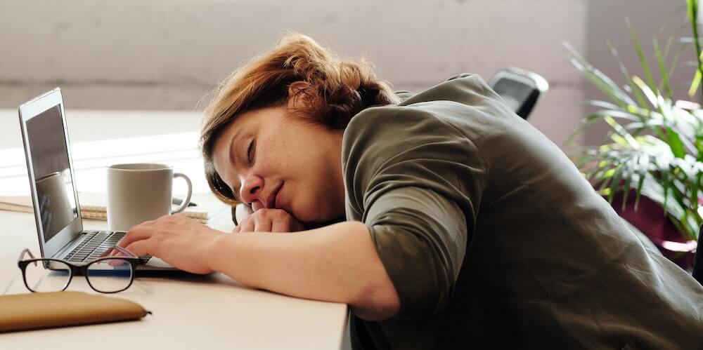 A woman-sleeping on her desk in front of her laptop