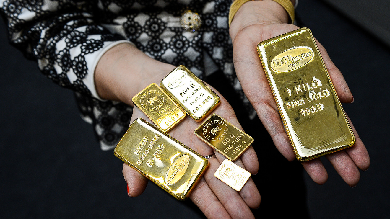 A woman holding different sizes of gold bars