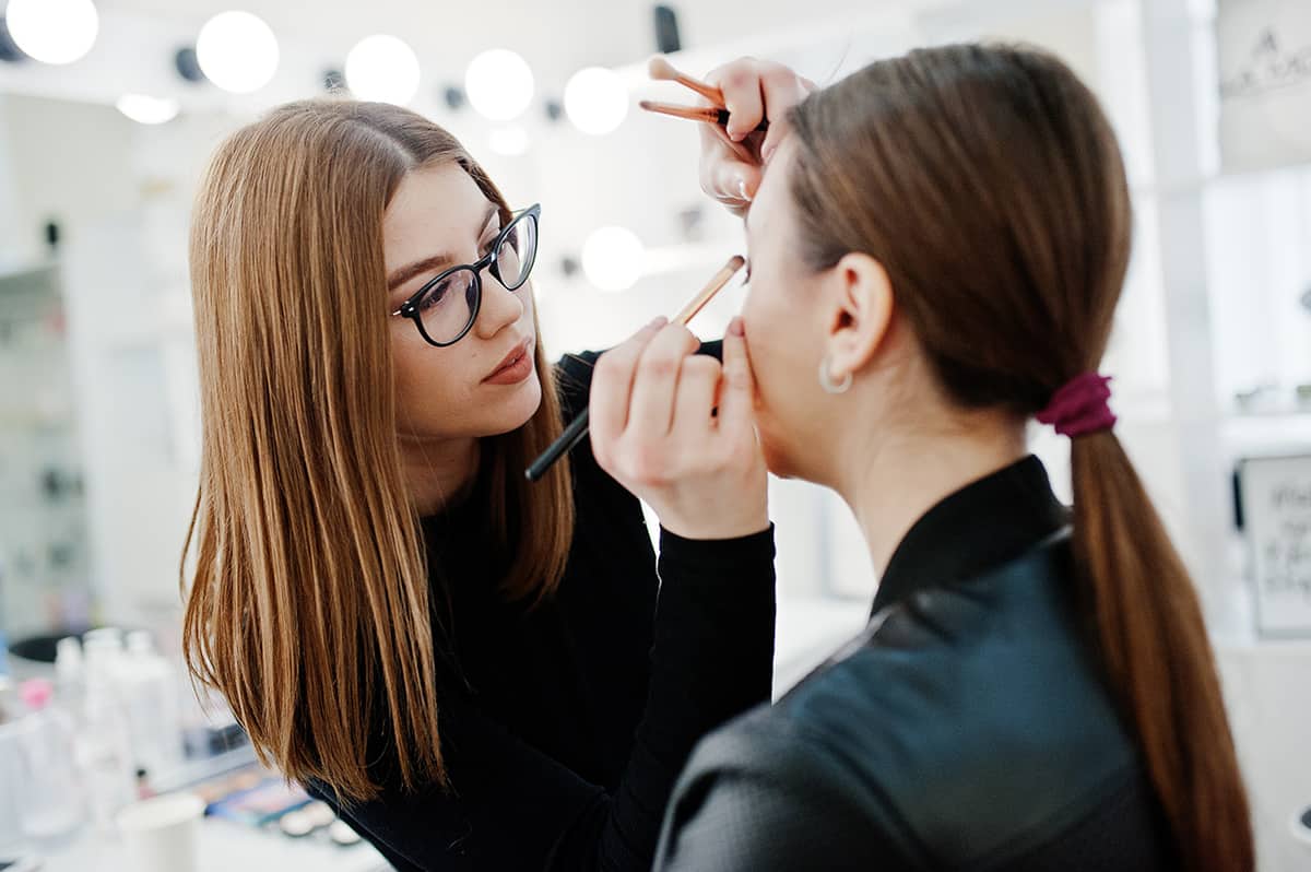 A female makeup artist applying makeup on a woman