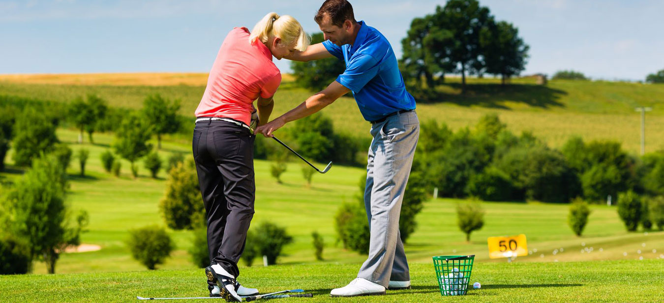 A man is teaching golf to a girl in a ground
