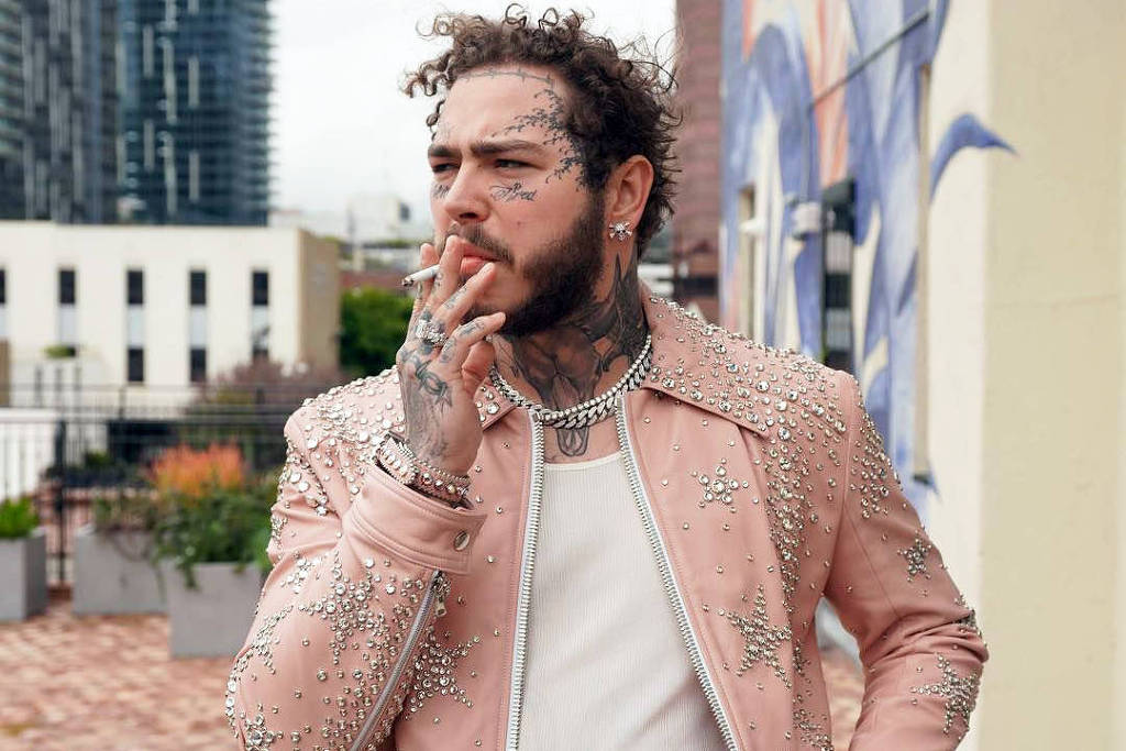 Post Malone wearing a pink jacket while holding a cigarette