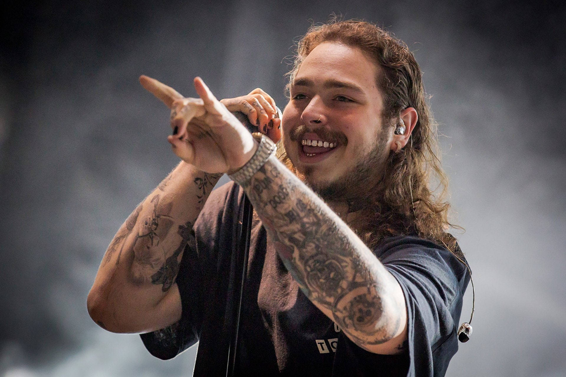 Post Malone wearing a black shirt while holding a mic