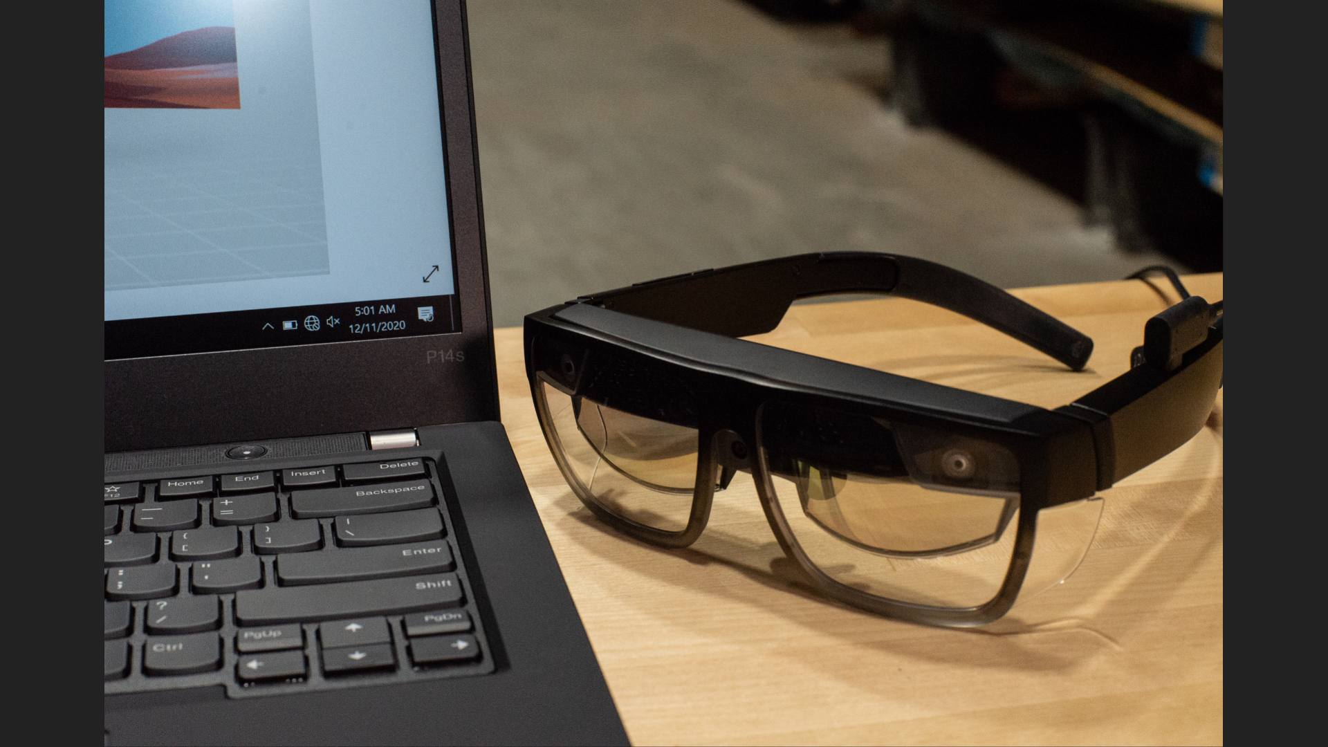 The ThinkReality smart glasses sitting beside a laptop