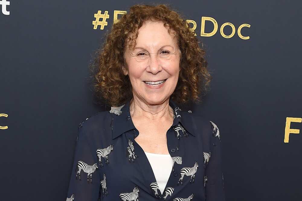 Rhea Perlman wearing a blue shirt as she smiles while attending an event
